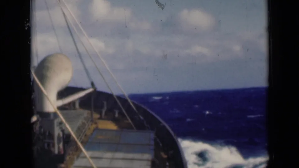 1947 8mm shipboard view, identified as Persian Gulf footage, showing the bow, rigging, and rough blue water ahead.
