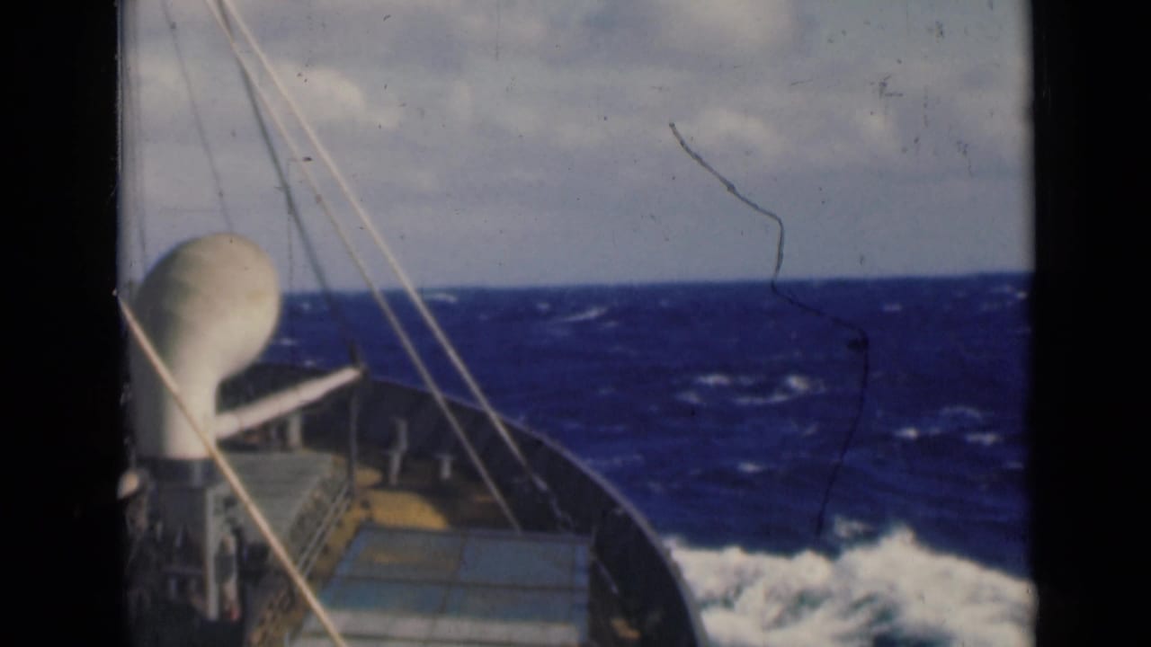 Forward deck and rigging of a ship as waves break alongside the bow.