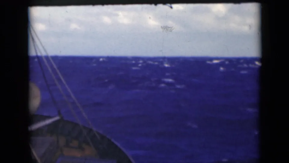 Deck-view 8mm frame of rolling blue water and scattered whitecaps, with rigging and part of the vessel along the left side.