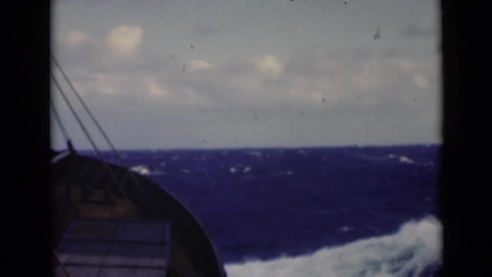 The final frame looks from the ship toward choppy blue water, a cloudy horizon, rigging, bow structure, and a bright wave at lower right.