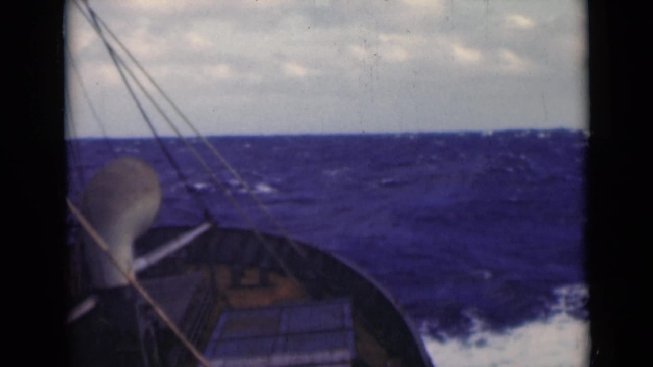 Bow of a sailboat points into choppy sea with rigging lines and whitecaps visible.