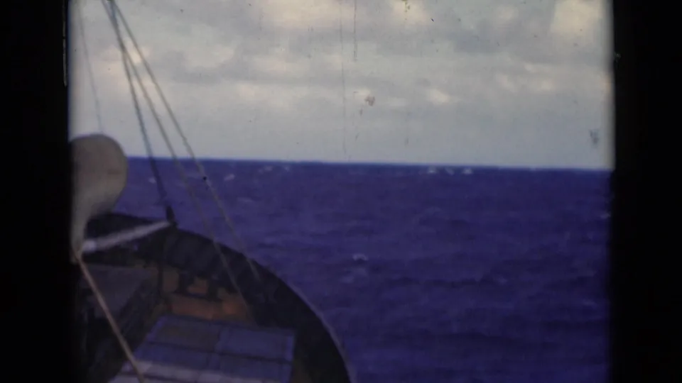 Bow view from a vessel on the Persian Gulf, with blue waves, rigging lines, cloudy sky, and visible 8mm film borders.