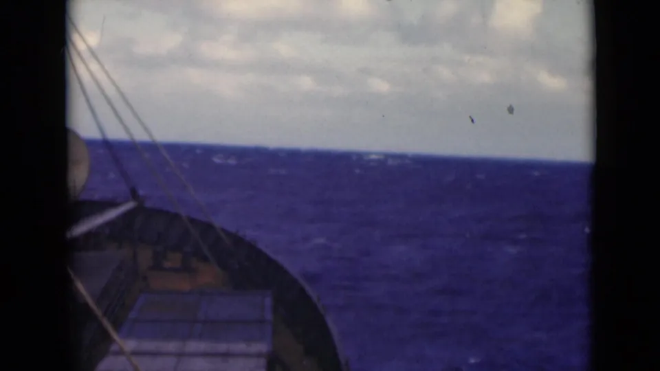 A passenger-facing deck view shows the left side of the boat bow, rigging, and choppy Persian Gulf water under a muted sky.