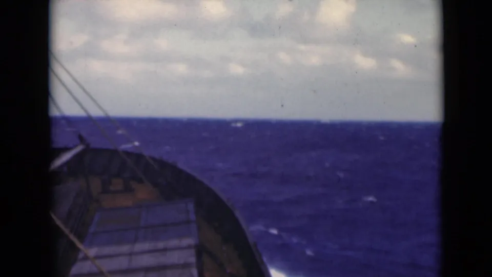 End frame of the 8mm clip with the boat bow, deck, rigging lines, and blue Persian Gulf waves below a cloudy horizon.