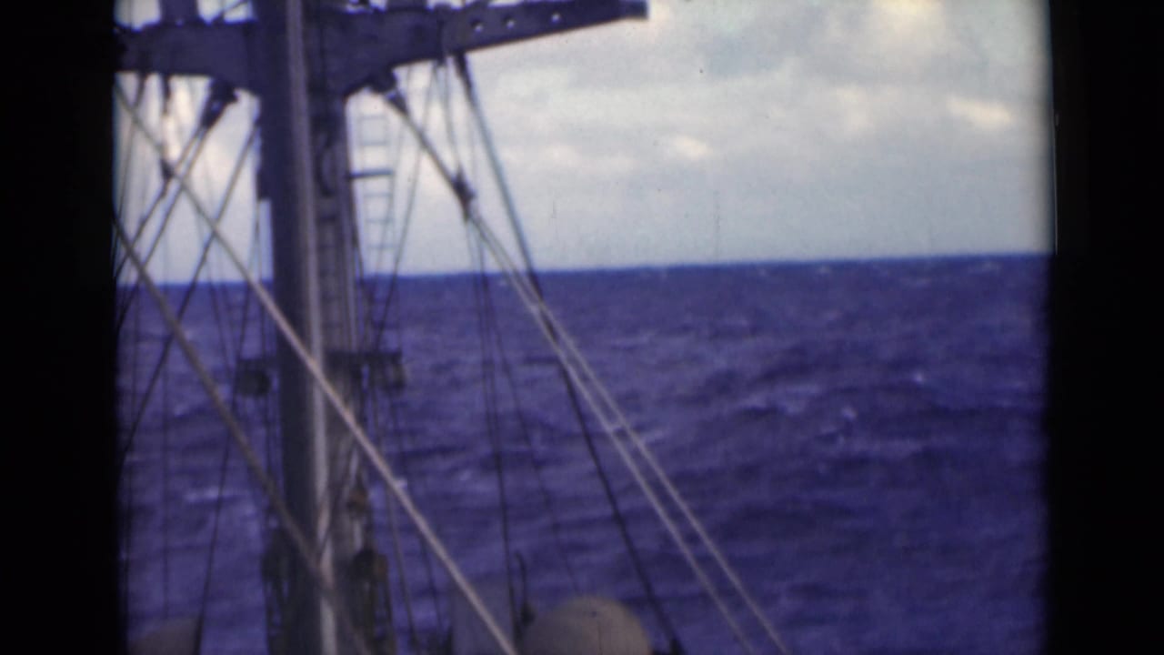 Mast, cables, and open ocean with a tilted horizon and cloudy sky.