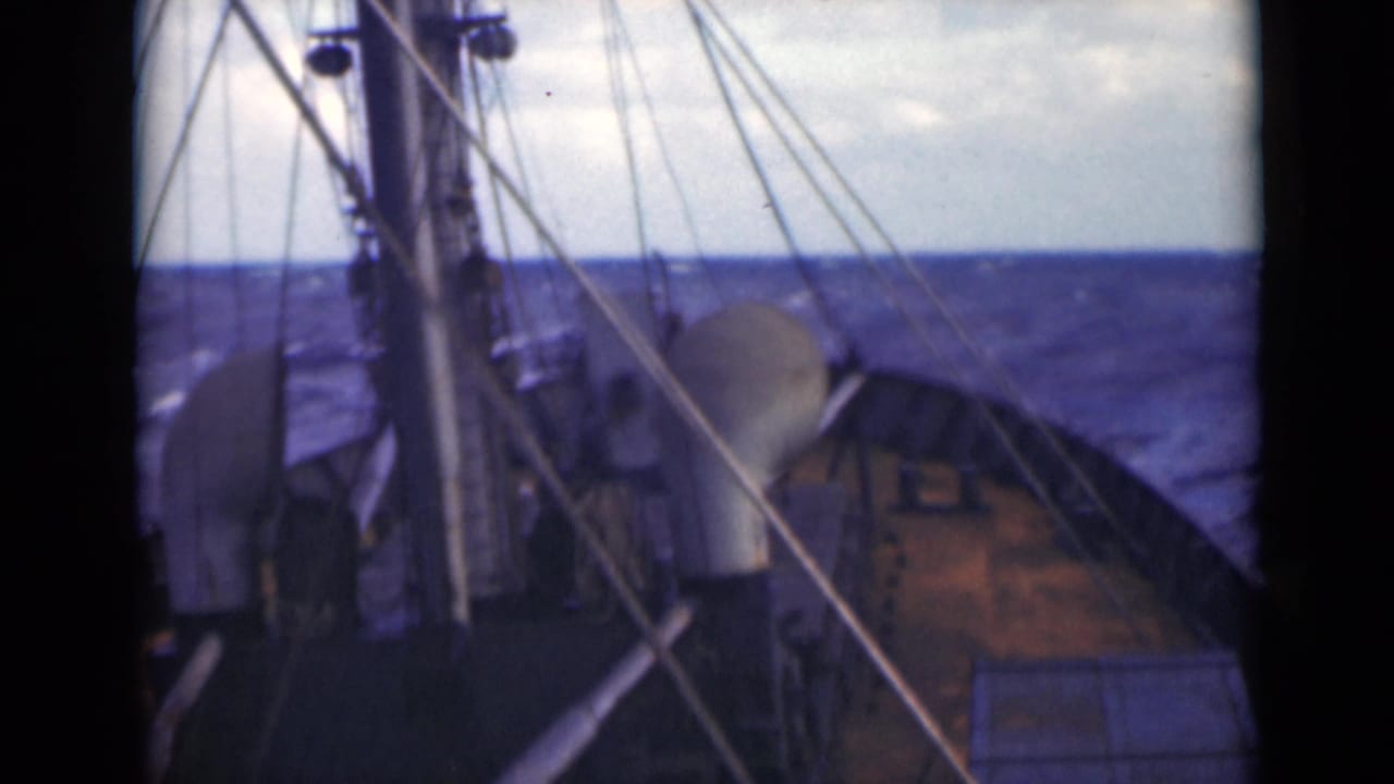 Archival 8mm frame showing a ship's deck, rigging, and bow facing rough open water, described in clip metadata as Persian Gulf footage.
