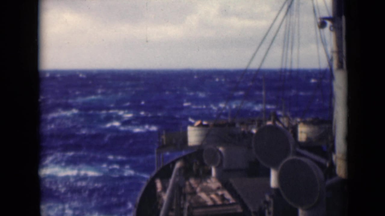 Bow and deck fittings appear at right as whitecapped waves fill the horizon.