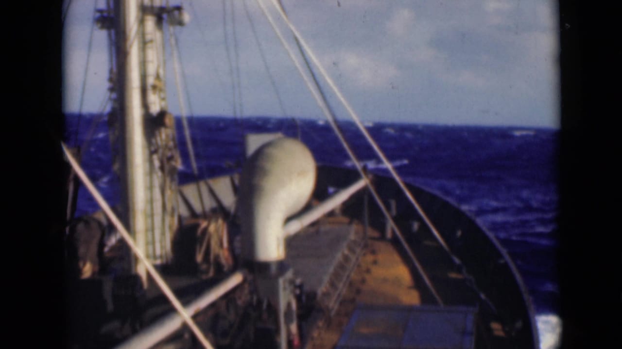 Ship bow and rigging face choppy blue water under a cloudy sky.