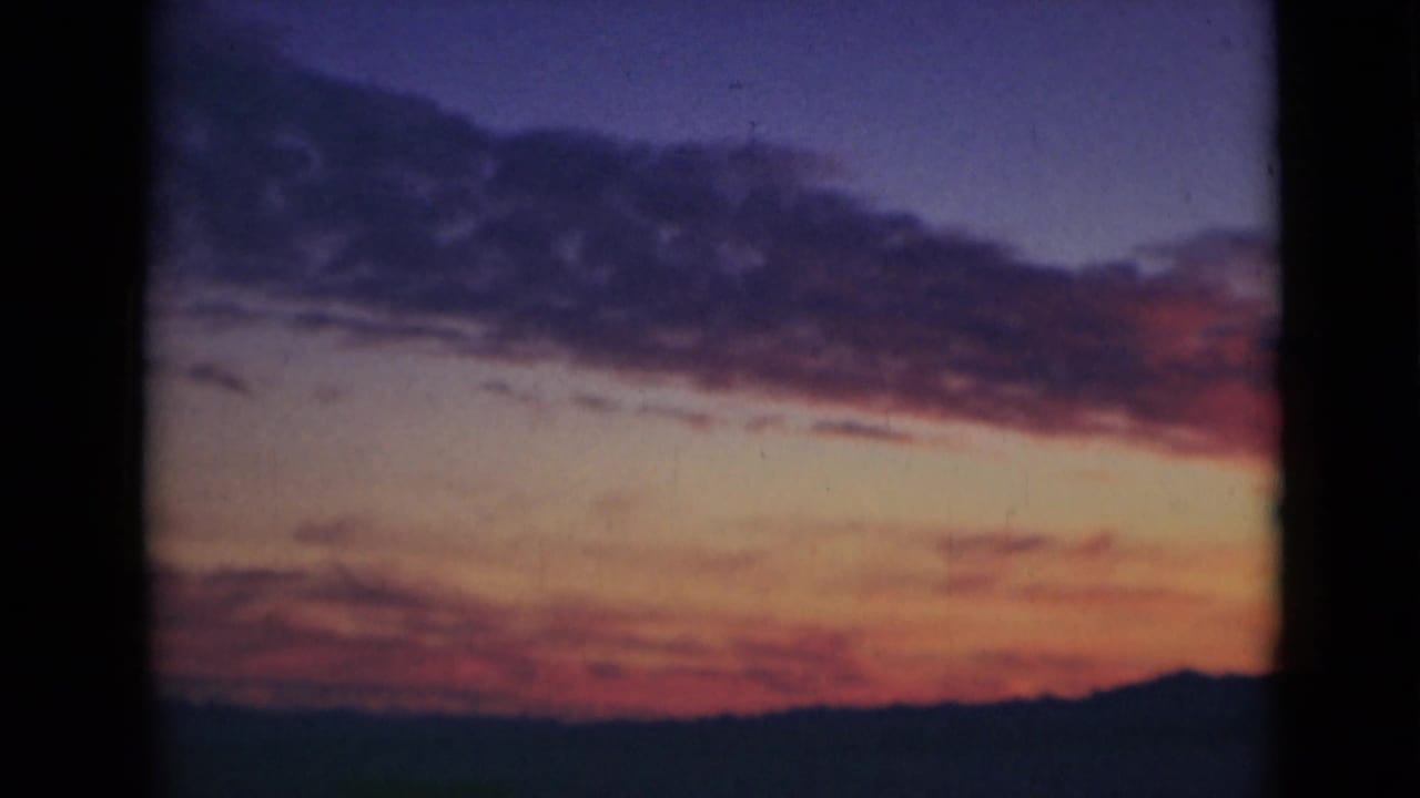 Sunset over a dark ocean horizon with orange and purple sky tones.