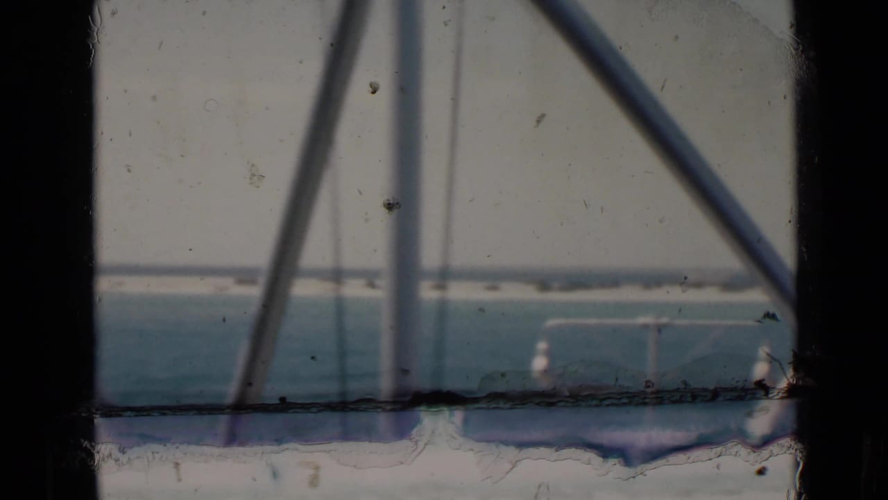 Blue water and distant shoreline seen through dark vessel framing.