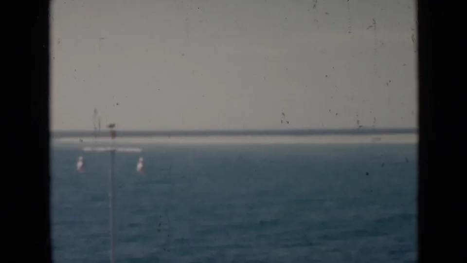 1947 8mm view of Persian Gulf water and horizon, partially blocked by dark frame edges and faint pier lamps.