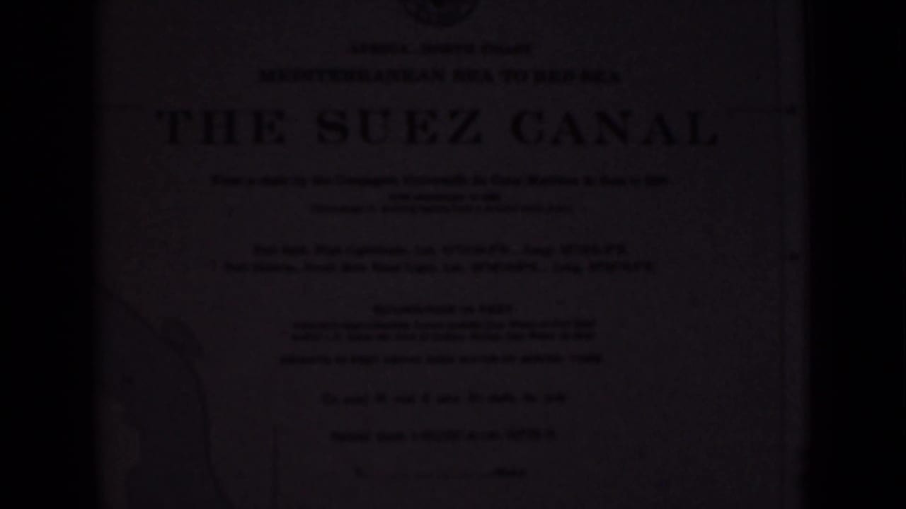 Dim frame of a Suez Canal informational plaque with large title and faint map outline.