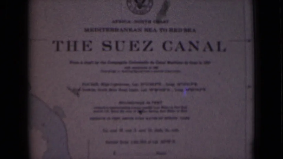 1946 8mm view of a Suez Canal informational plaque in Egypt, showing the title, emblem, route description, and left-side map outline.