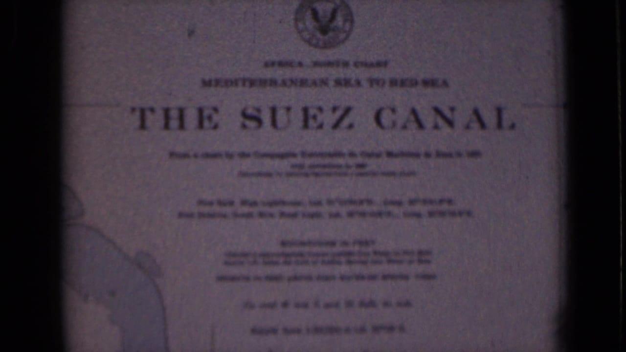 Bright 1946 8mm frame of the Suez Canal plaque in Egypt, with the title, smaller route wording, top emblem, and map outline visible.