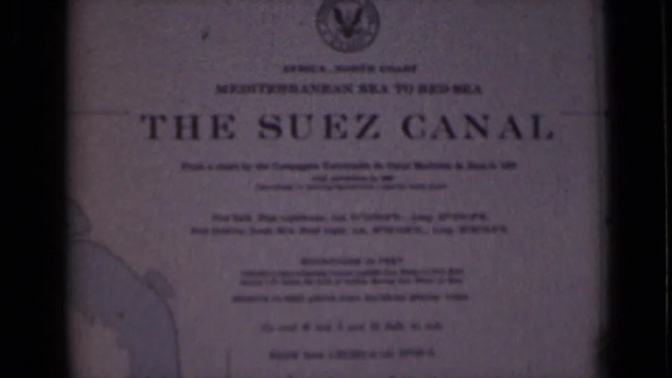 Bright 1946 8mm frame of the Suez Canal plaque in Egypt, with the title, smaller route wording, top emblem, and map outline visible.