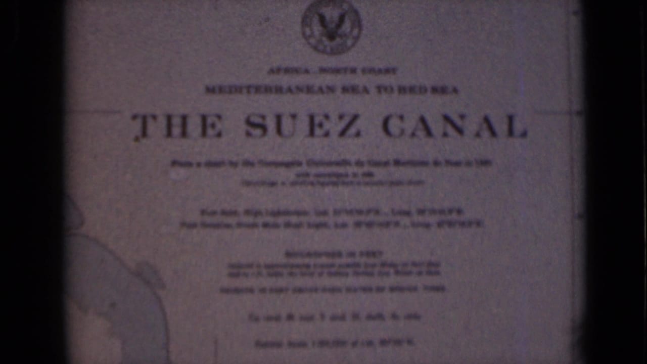 1946 8mm frame of the Suez Canal plaque in Egypt, framed by dark borders and showing the title, emblem, text, and partial map.