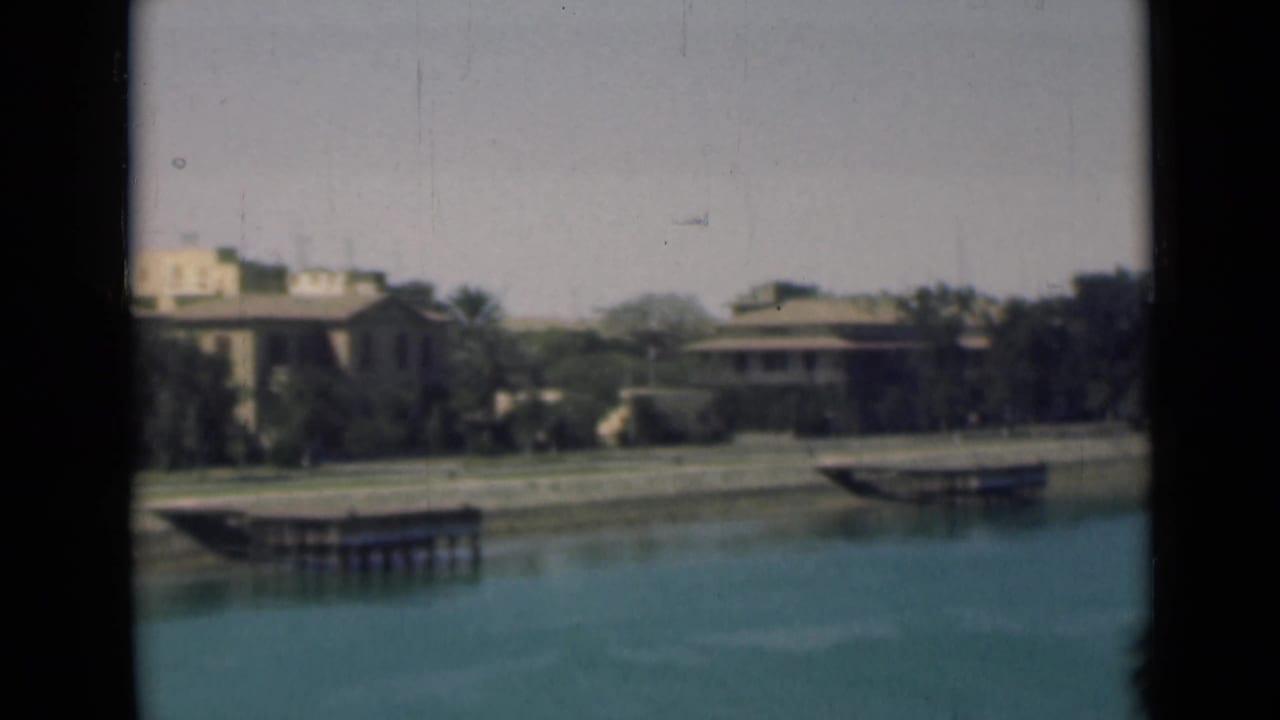 Canal water with tan buildings, trees, and small landing platforms in the distance.