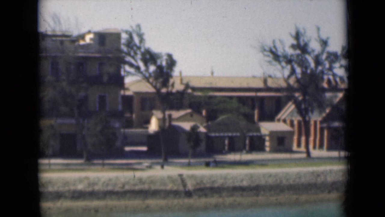 Canal-side buildings and trees viewed through dark window-frame edges.