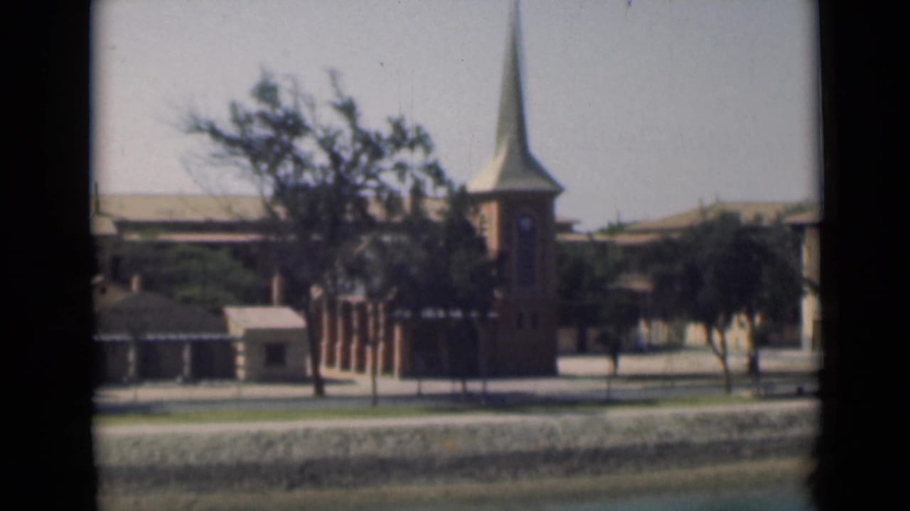 1946 Suez Canal scene showing a church tower and steeple among trees and low waterfront buildings.