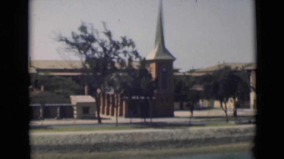 1946 Suez Canal scene showing a church tower and steeple among trees and low waterfront buildings.