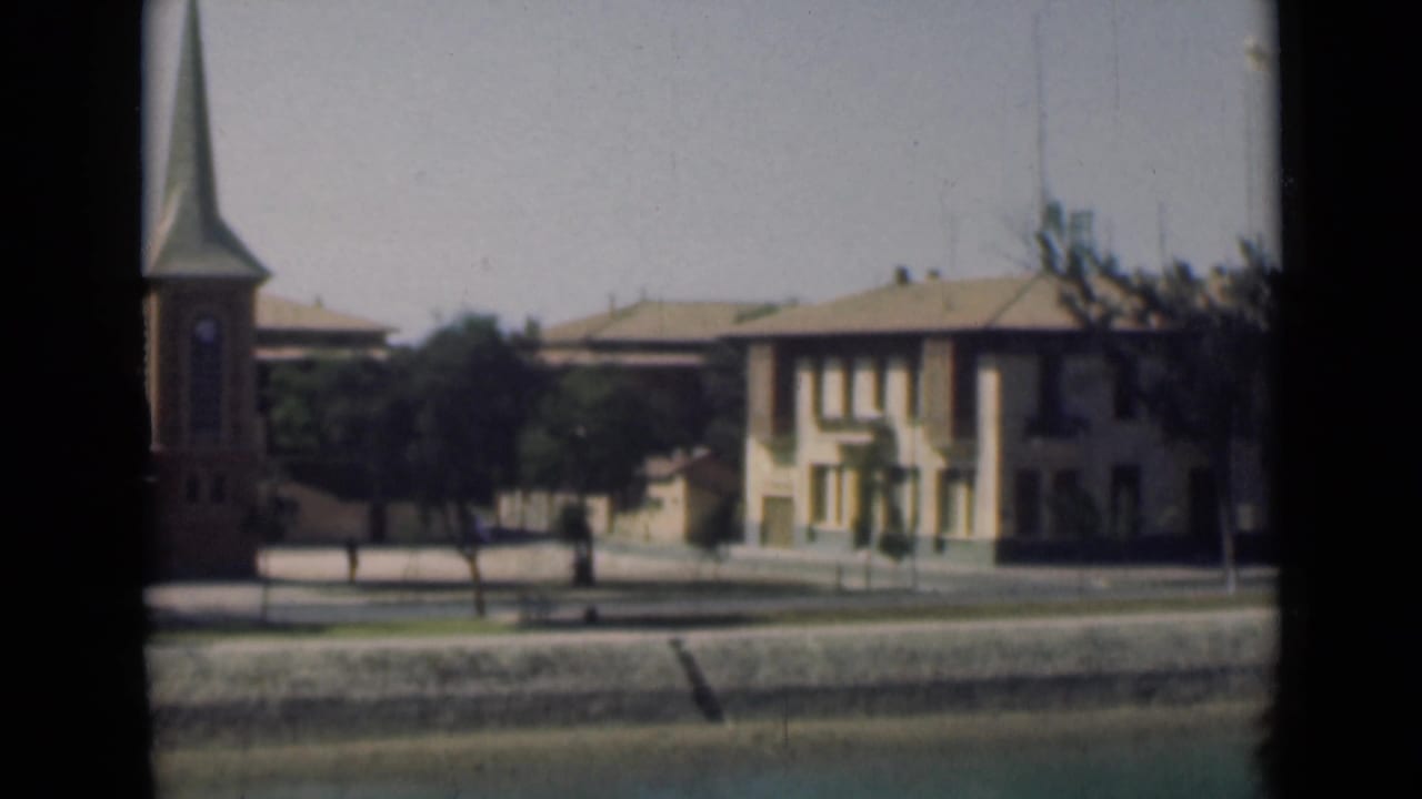 Moving 1946 Suez Canal area view with the church partly cropped, a pale building centered, trees, and a road beside a low canal edge.