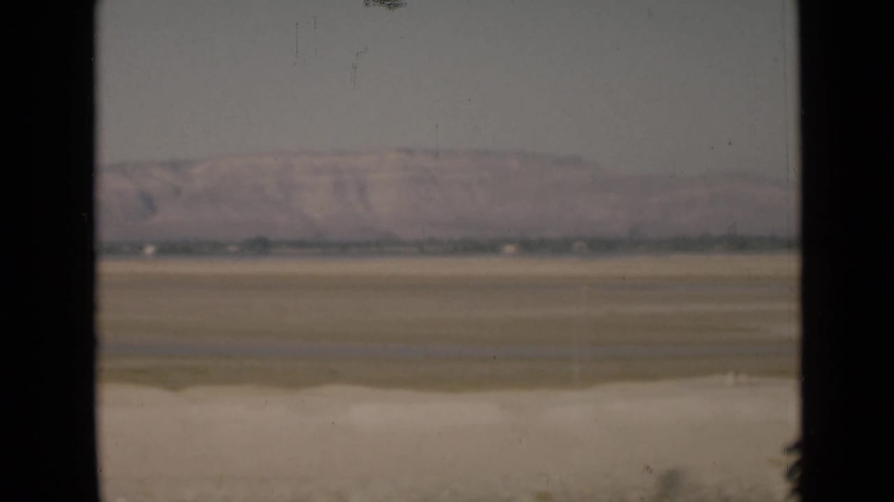 1946 Suez Canal region desert terrain with hazy distant hills, viewed through a dark window or vehicle frame.