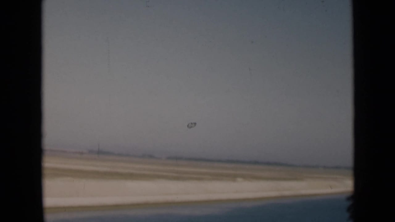 Desert road and horizon seen through a dark vehicle window frame.