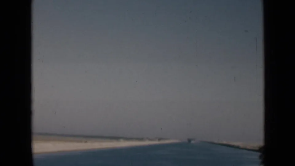 Forward-facing 1946 Suez Canal view from a vessel, with water leading toward distant sandy banks.