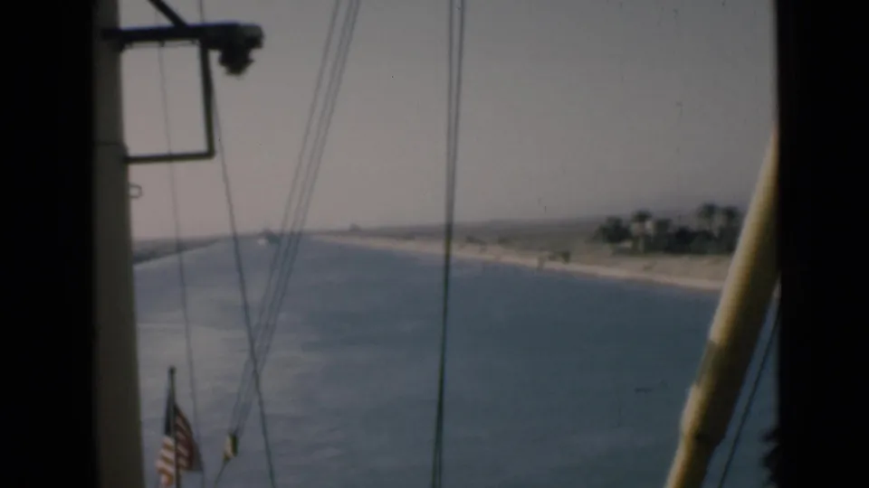 Onboard 8mm frame from the Suez Canal showing an American flag, rigging, waterway, and low Egyptian shoreline.