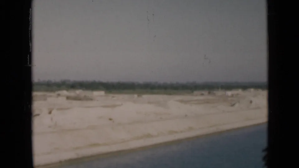 1946 Egypt canal passage view with water in the foreground, pale sandy land, and distant trees beneath a muted sky.