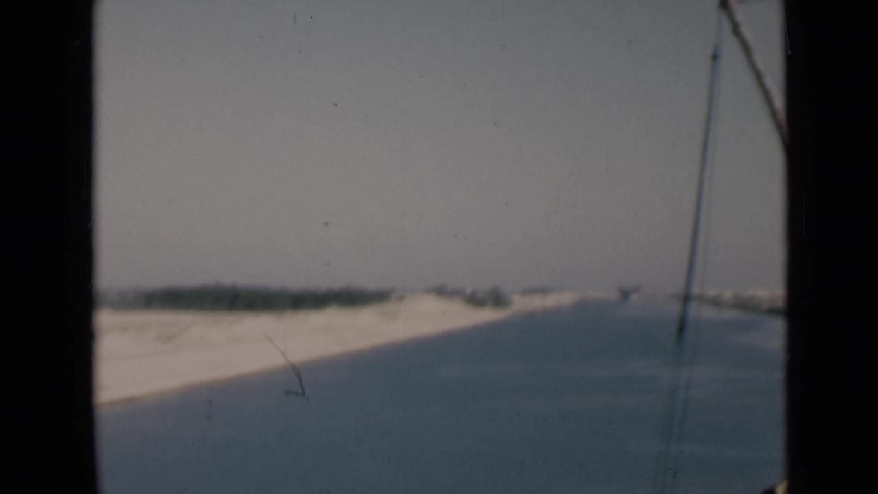 Suez Canal shoreline in 1946 8mm footage, filmed from a boat with rigging entering the right side of the frame.