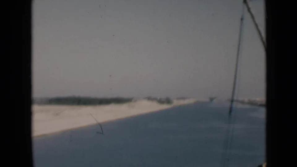 Suez Canal shoreline in 1946 8mm footage, filmed from a boat with rigging entering the right side of the frame.