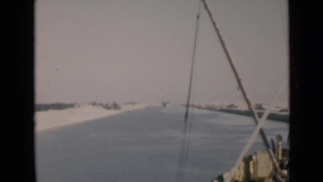Forward canal view framed by boat rigging and dark film borders.