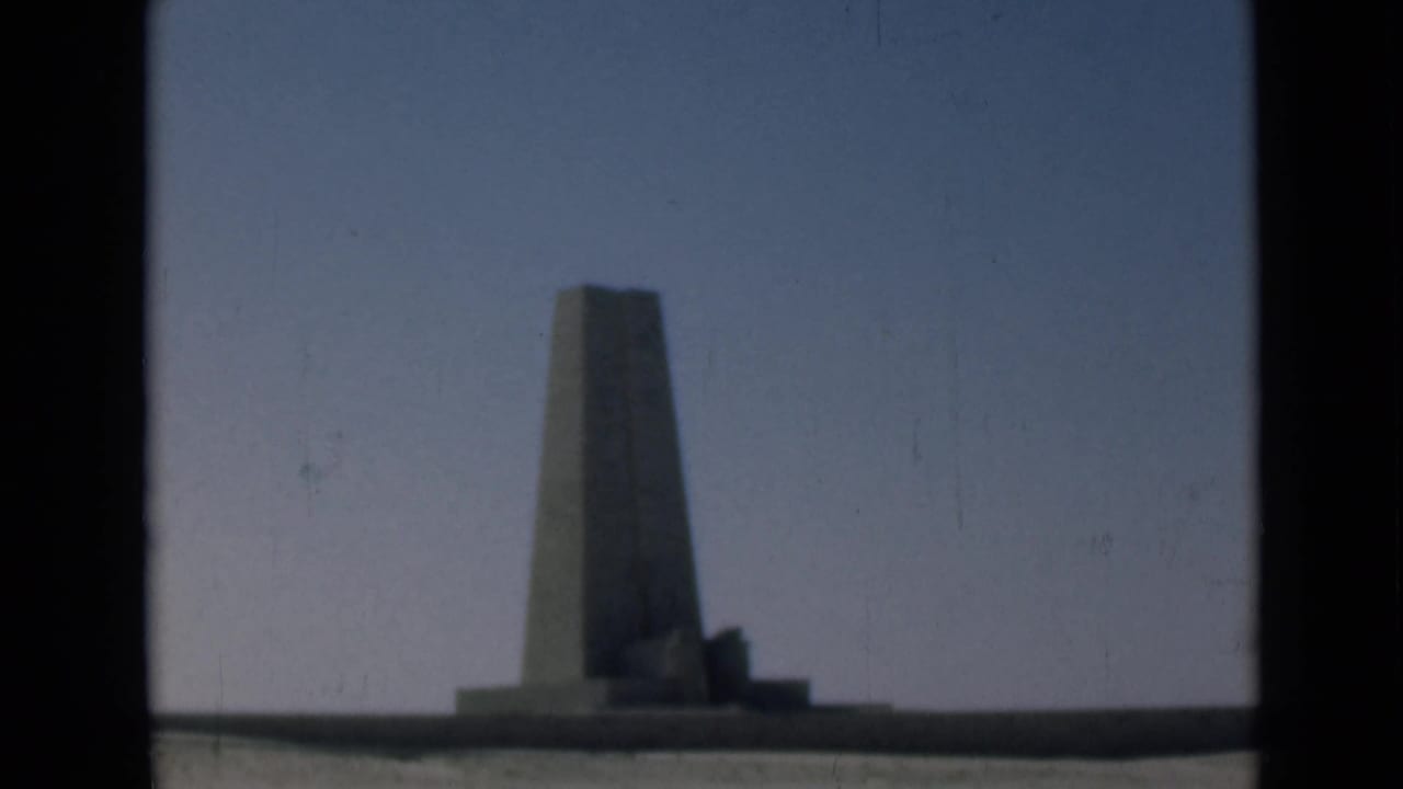 Final 1946 Suez Canal region frame showing the obelisk-like monument and low base against a blue sky, softened by film age.