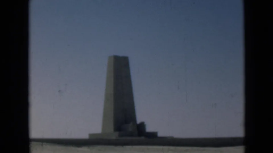 Final 1946 Suez Canal region frame showing the obelisk-like monument and low base against a blue sky, softened by film age.