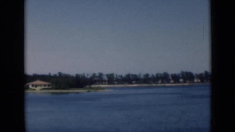 Final 1946 Suez Canal frame with broad blue water, distant trees, low shoreline structures, and visible 8mm film borders.