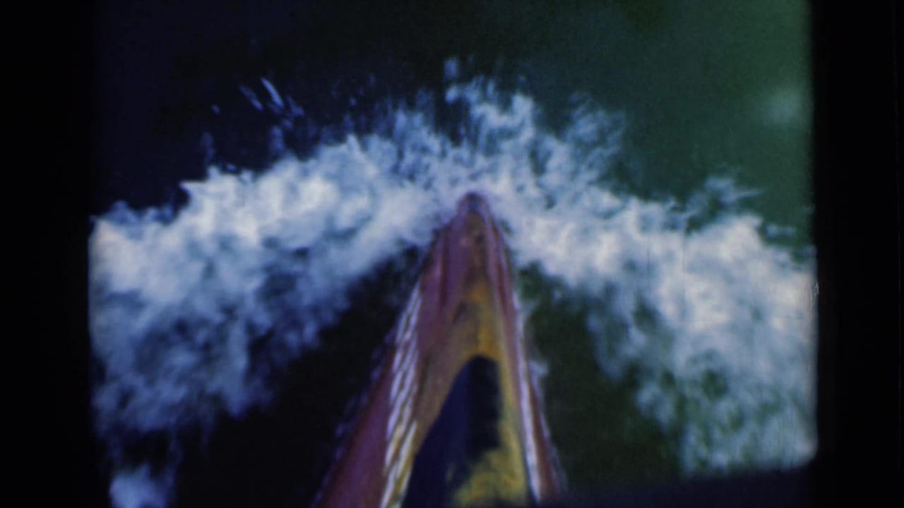 The centered prow continues forward through choppy water, with broad white wake visible on both sides of the frame.