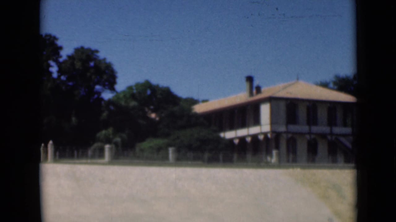 1946 Suez Canal frame of a veranda-style building with a tiled roof, seen from outside across a pale wall.