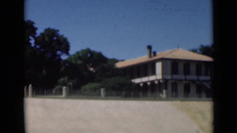 1946 Suez Canal frame of a veranda-style building with a tiled roof, seen from outside across a pale wall.