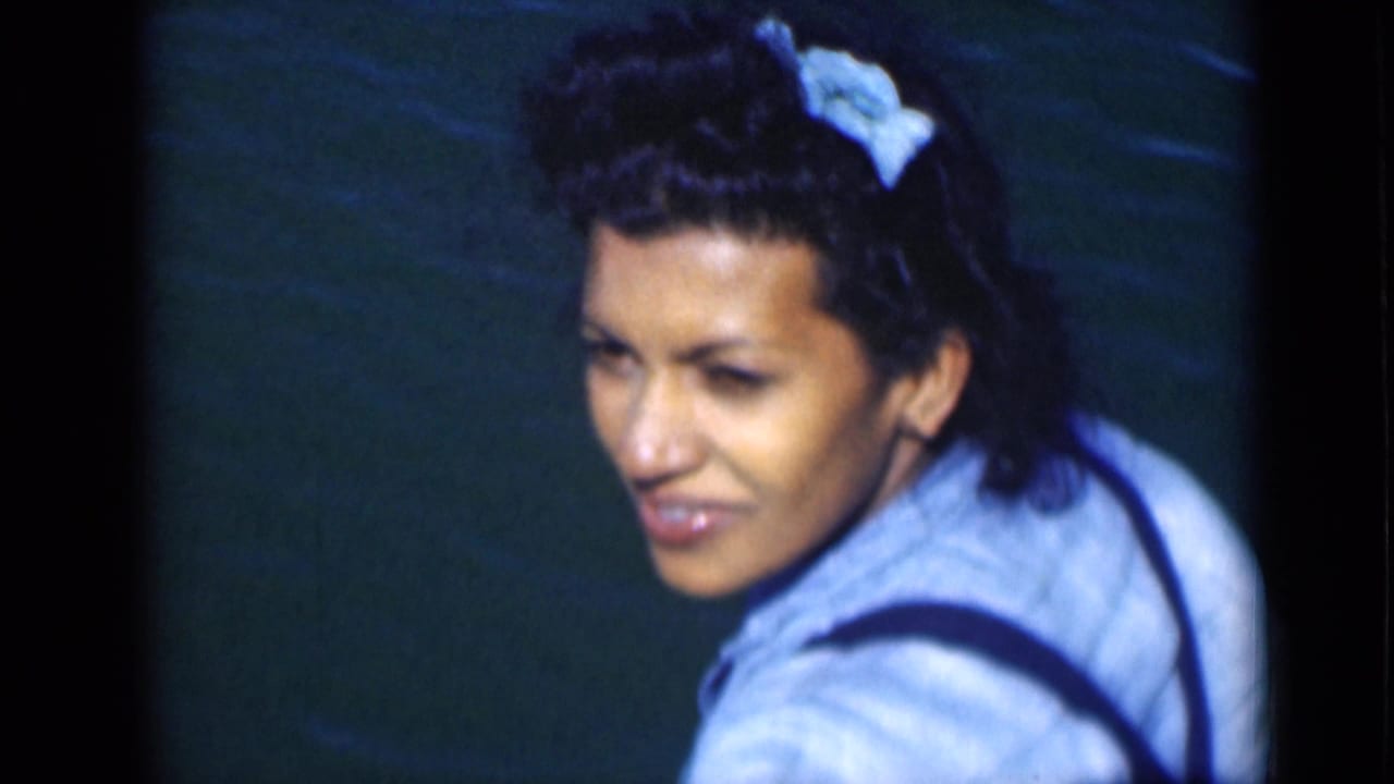 In 1946 Suez Canal home-movie footage, a woman with a blue hair bow turns toward the camera near dark water.