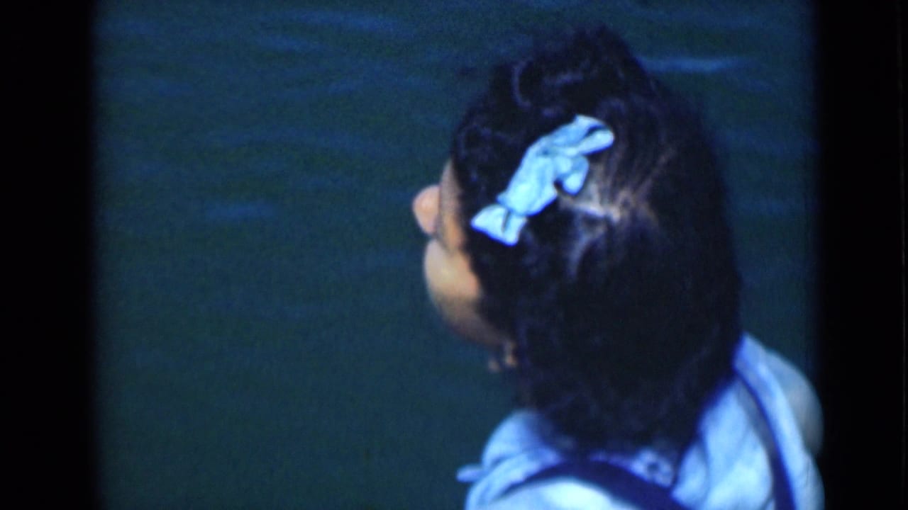 The woman faces away in the final frame, with her blue hair bow and pale top set against dark water.