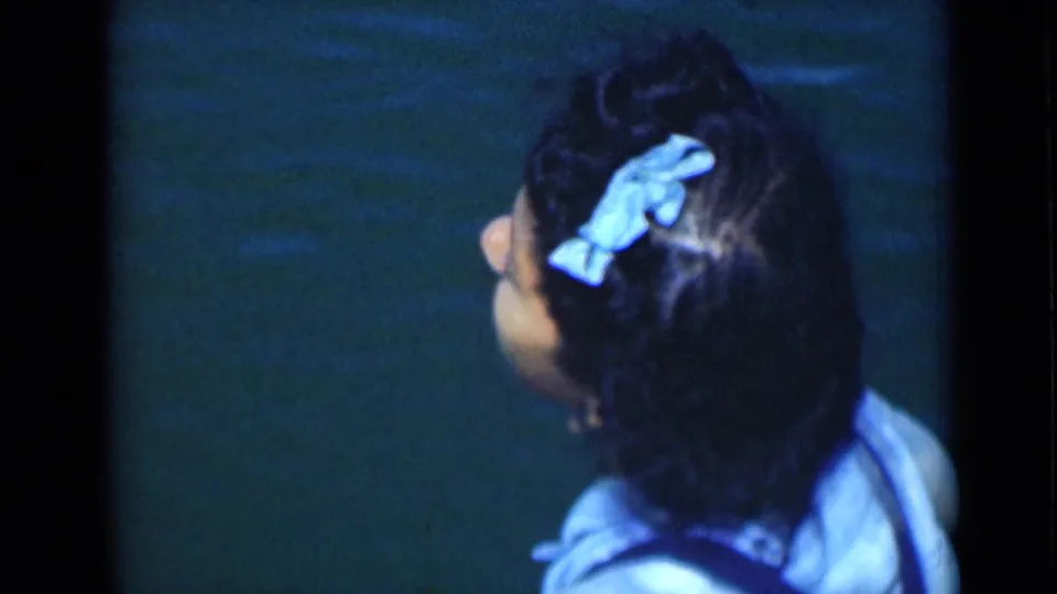 The woman faces away in the final frame, with her blue hair bow and pale top set against dark water.