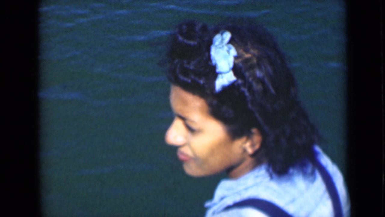 Adult woman in profile aboard or near a boat on the Suez Canal, with green-blue water behind her in 1940s 8mm footage.
