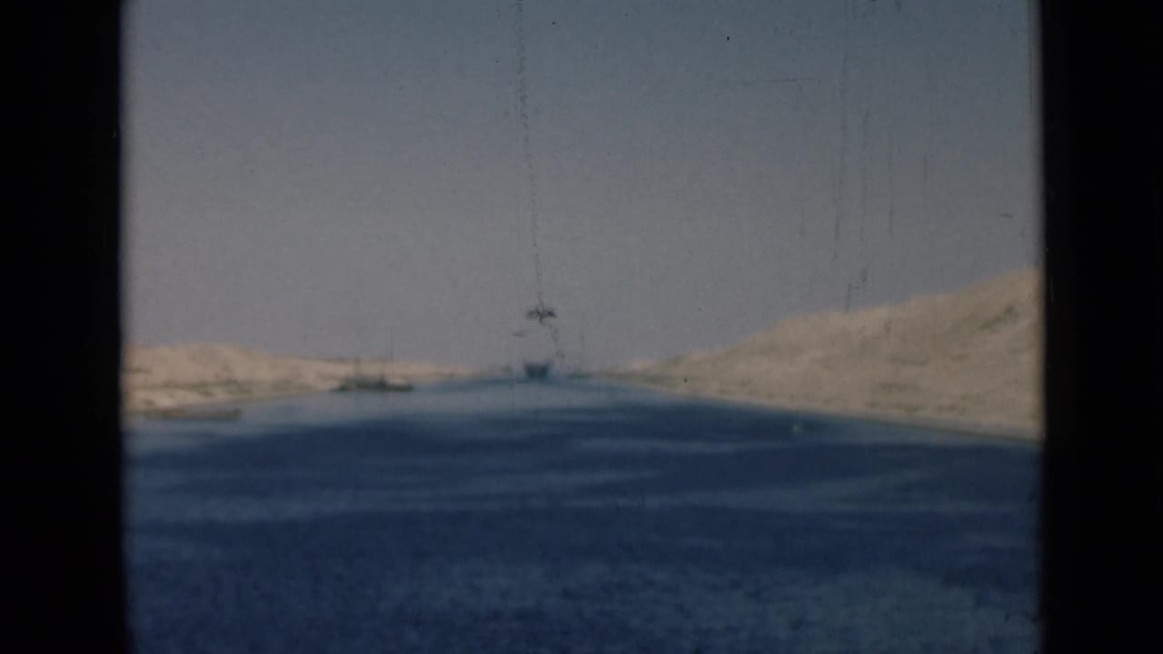 1946 Suez Canal view showing broad blue water, pale desert banks, and a distant vessel or structure near the horizon.