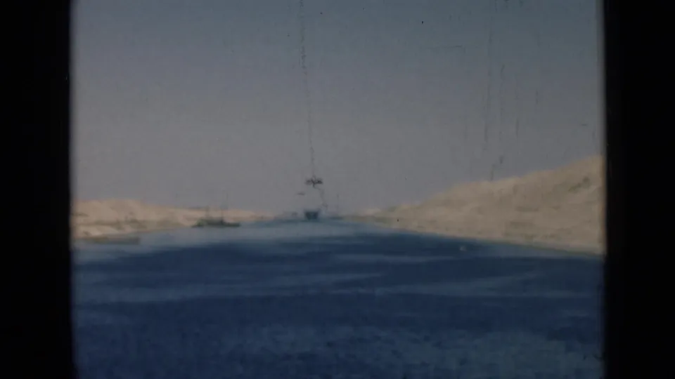1946 Suez Canal view showing broad blue water, pale desert banks, and a distant vessel or structure near the horizon.