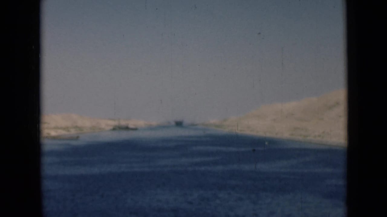 Soft 8mm frame of the Suez Canal in 1946, with blue water, pale banks, and dark borders from the film scan.