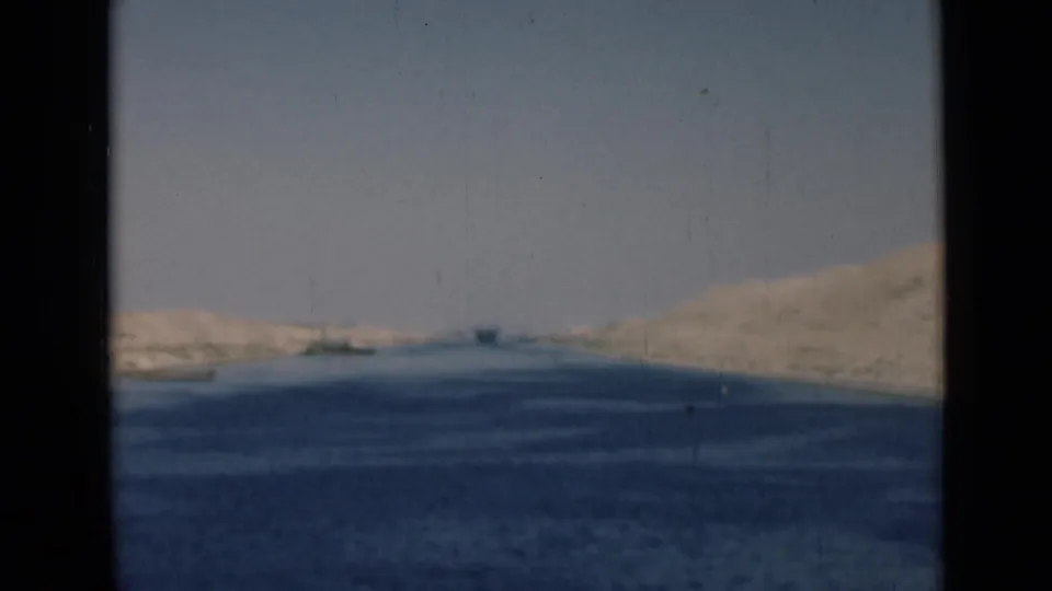 Soft 8mm frame of the Suez Canal in 1946, with blue water, pale banks, and dark borders from the film scan.