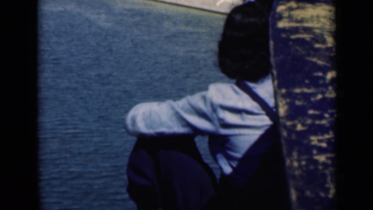 A seated man in a light shirt and dark trousers watches the Suez Canal water in this 1946 home-movie frame.