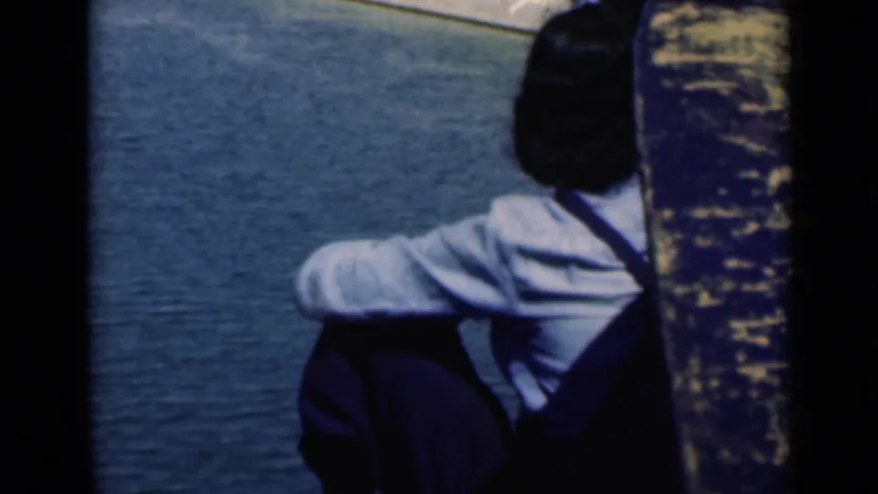 A seated man in a light shirt and dark trousers watches the Suez Canal water in this 1946 home-movie frame.
