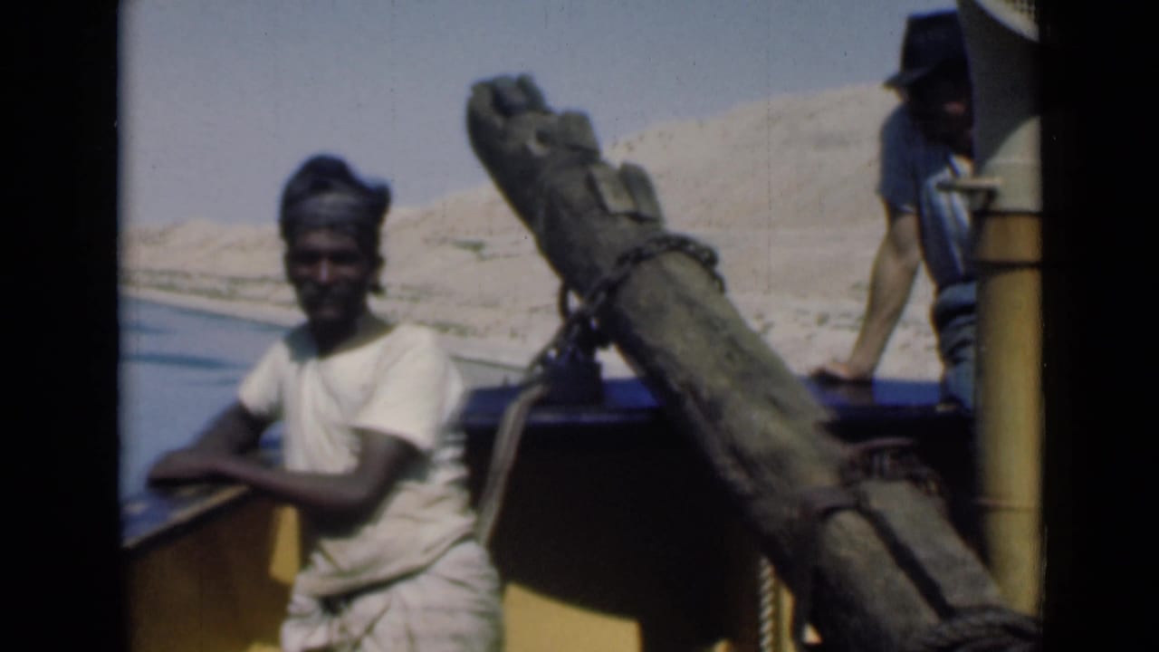 1946 Suez Canal home-movie frame showing a man by the boat rail, with a large pole and a second man partly visible at the stern.